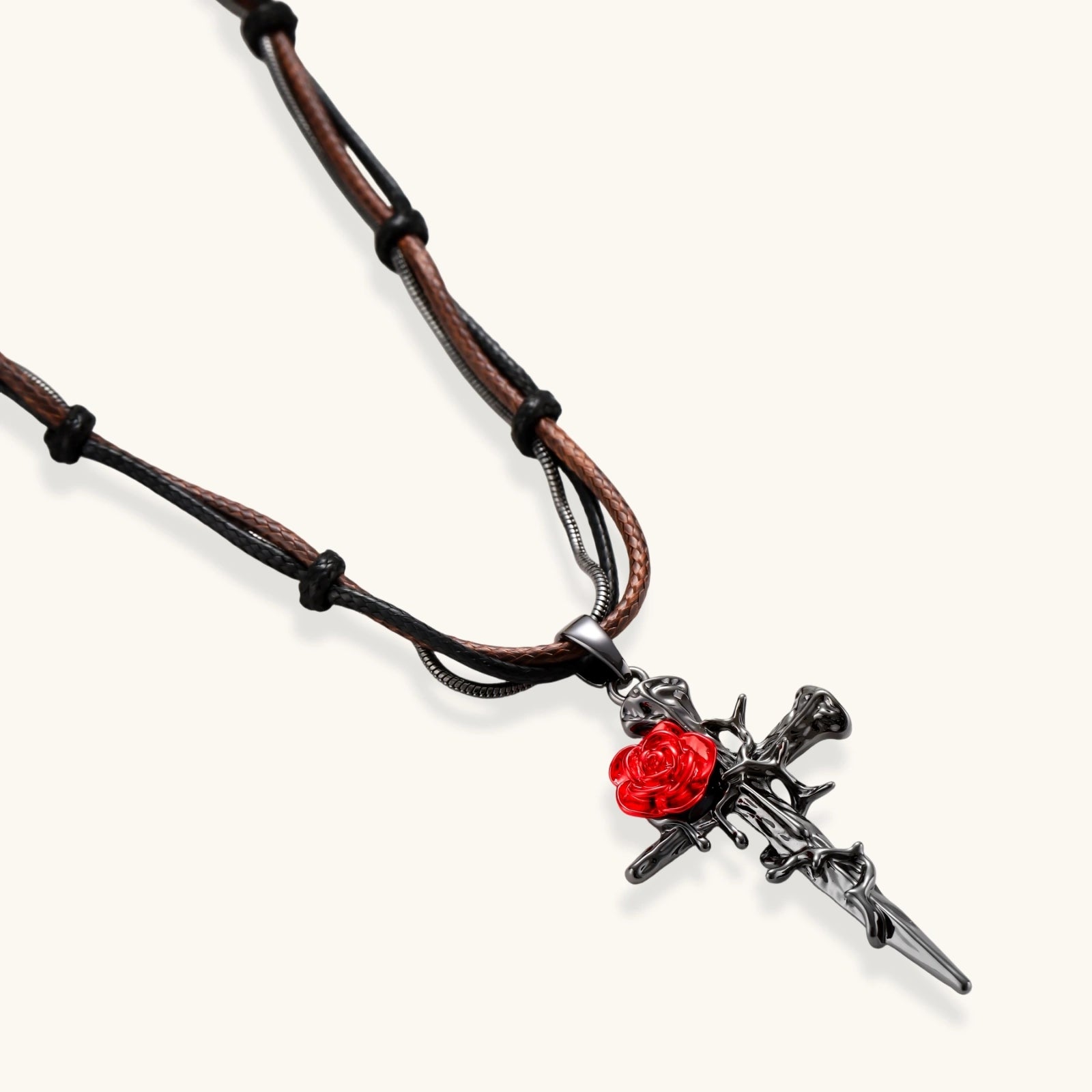 Gothic cross pendant with red enamel rose and thorn details on adjustable brown cord necklace against white background.