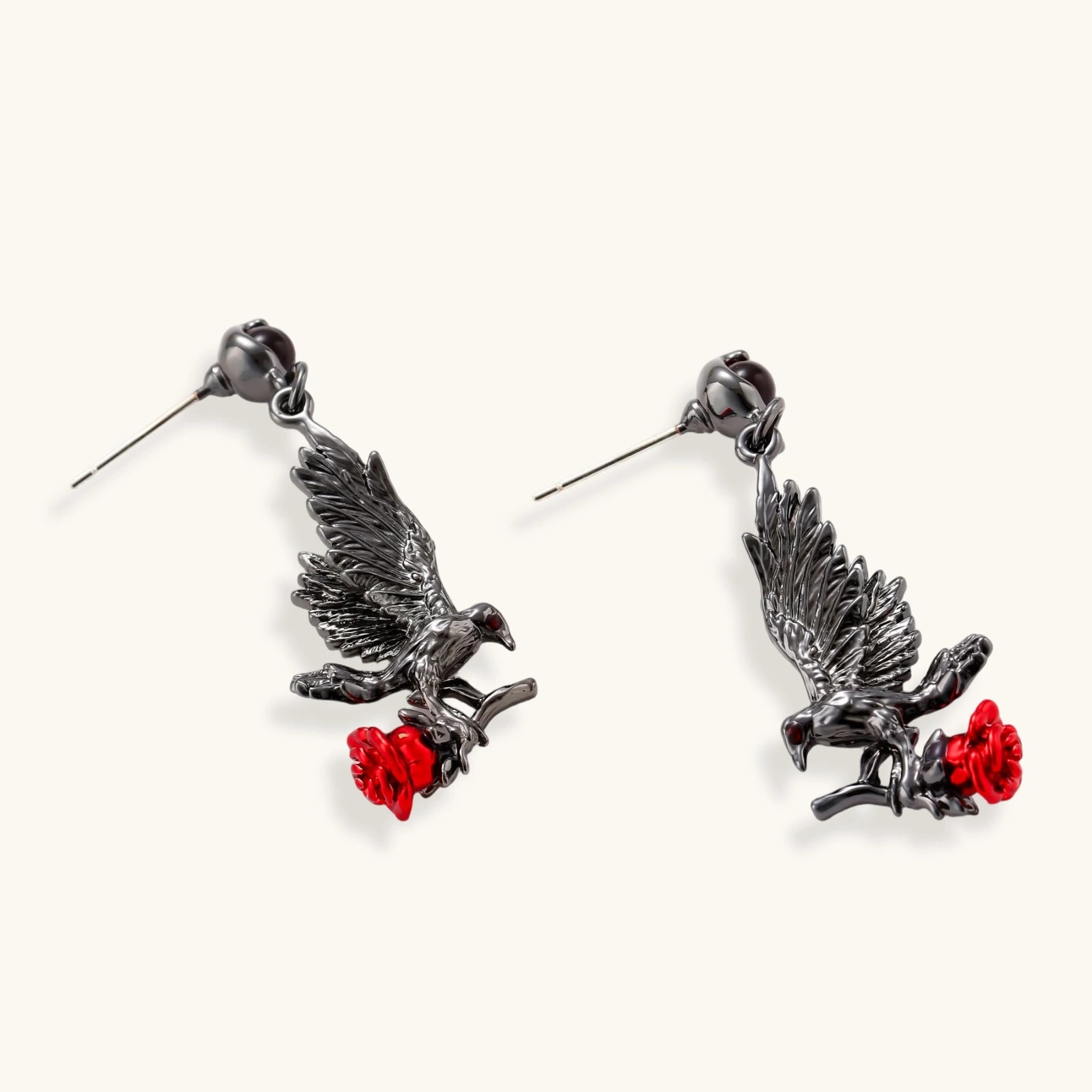 Dark gunmetal raven earrings with red rose details, featuring detailed bird wings and S925 silver posts on cream background.
